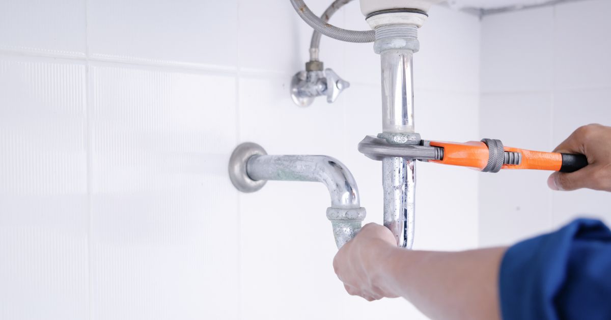 man tightening plumbing pipes