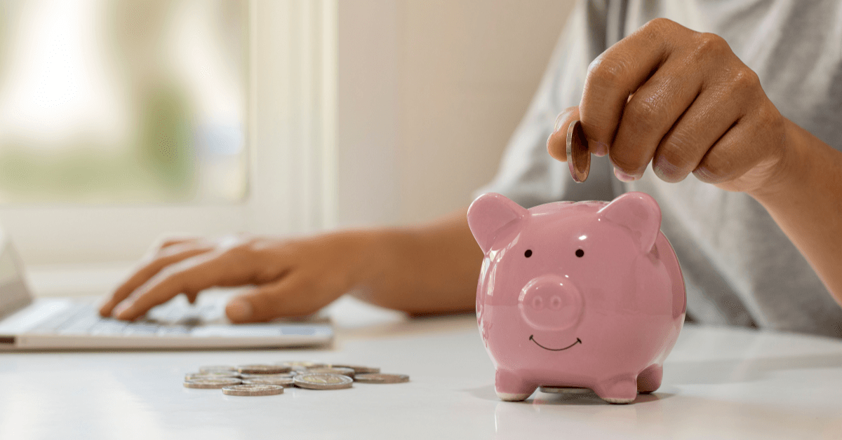 person putting money on piggy bank
